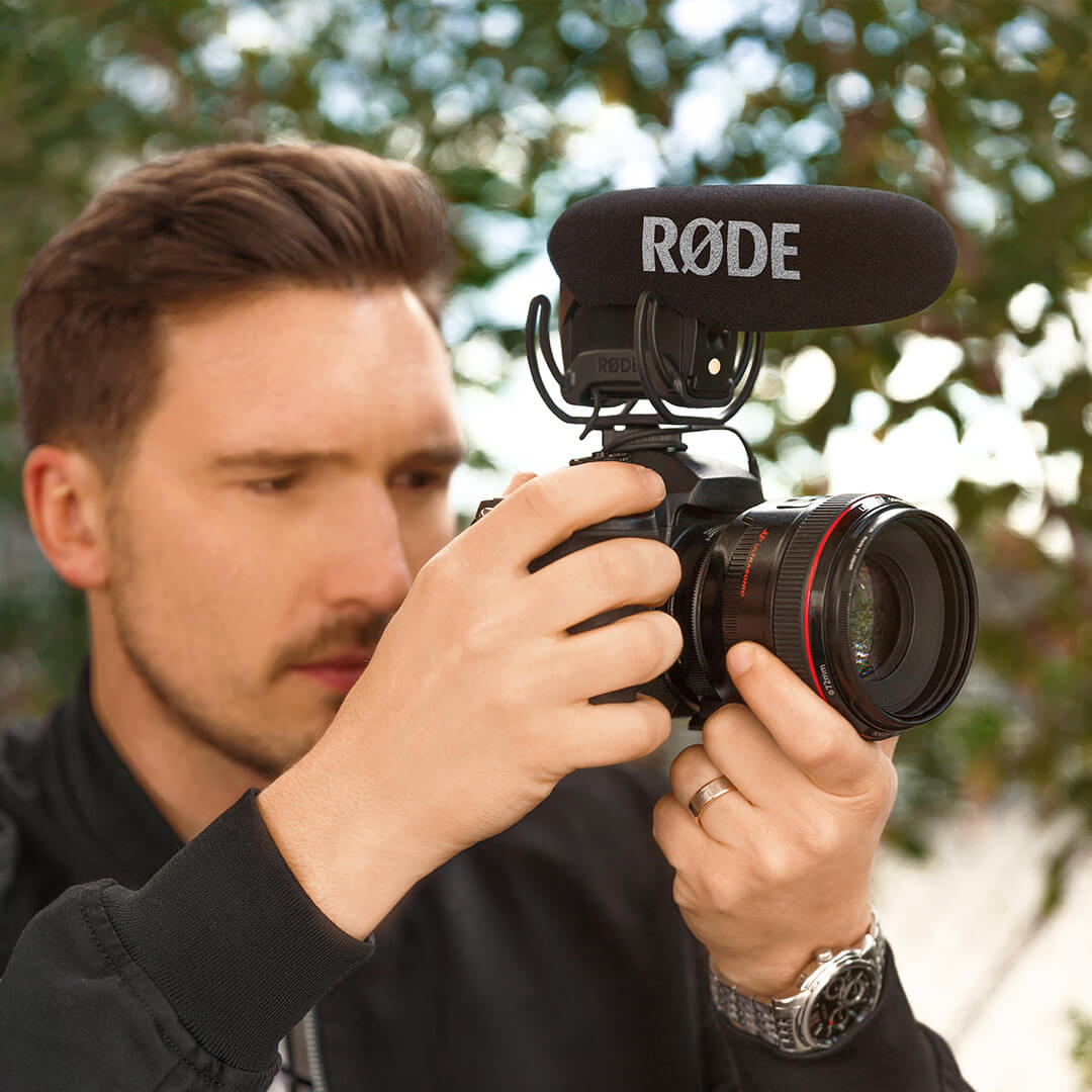 Man holding camera with VideoMic Pro mounted on top