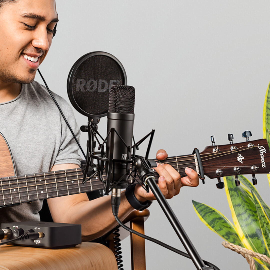 Man recording vocals and acoustic guitar with Rode NT1 Condenser Microphone on SM6 attached to microphone stand