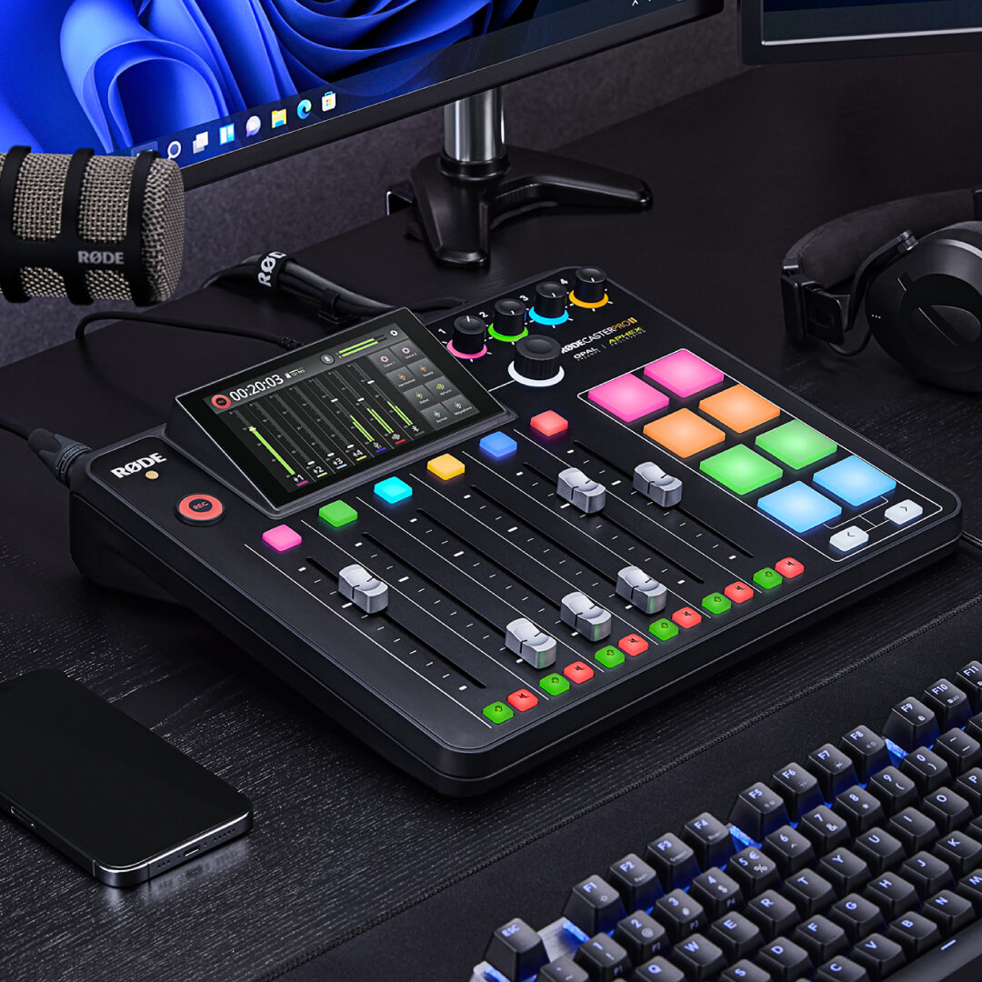 RØDECaster Pro II on table in front of computer screen with PodMic and mobile phone next to it
