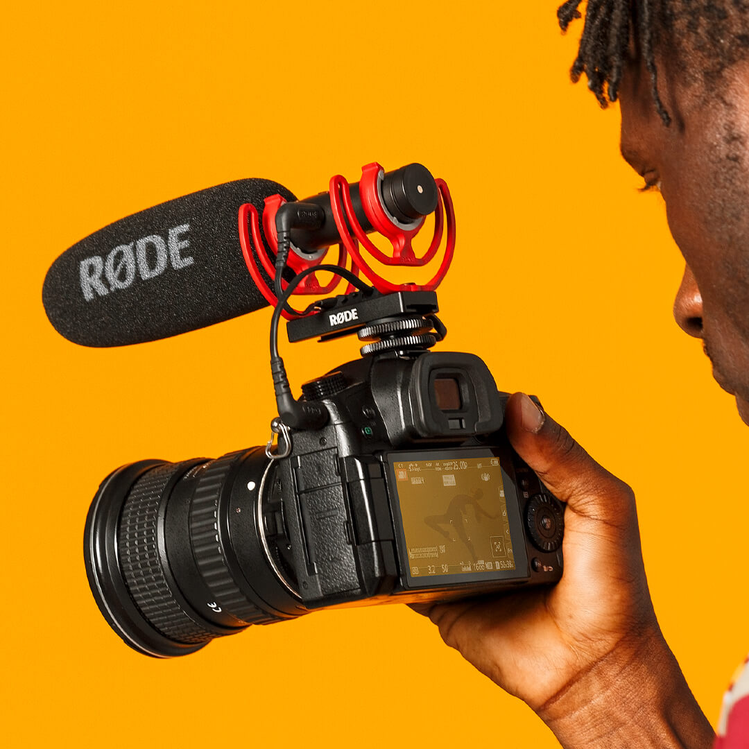 Man using camera with VideoMic NTG in yellow backdrop