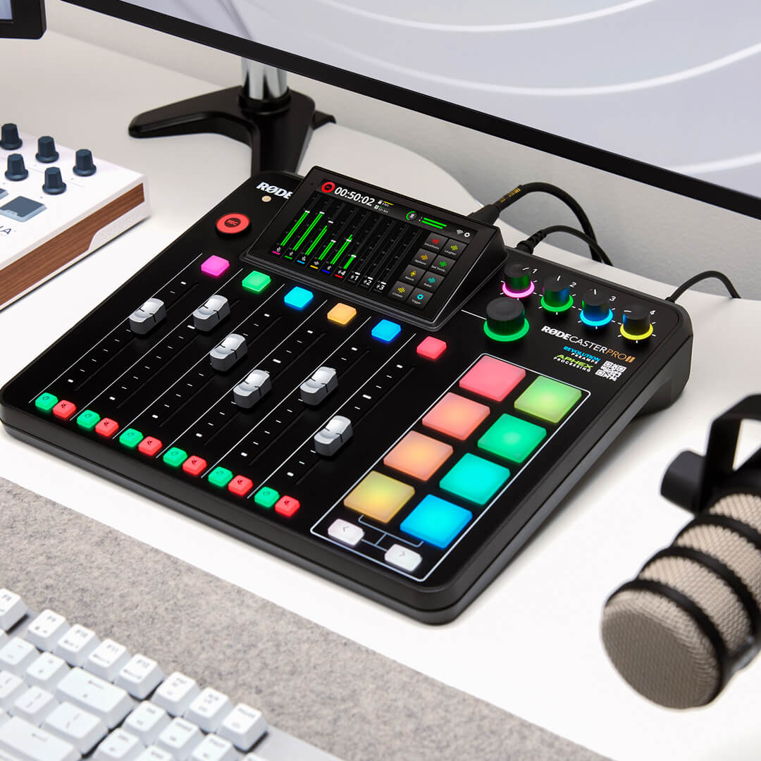 RØDECaster Pro II on white table with faders up and meter levels showing
