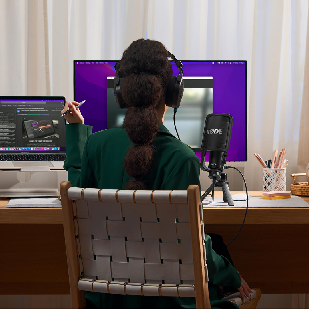 Girl at desk wearing NTH-100 and holding pencil in front of computer screen with NT-USB+ next to her