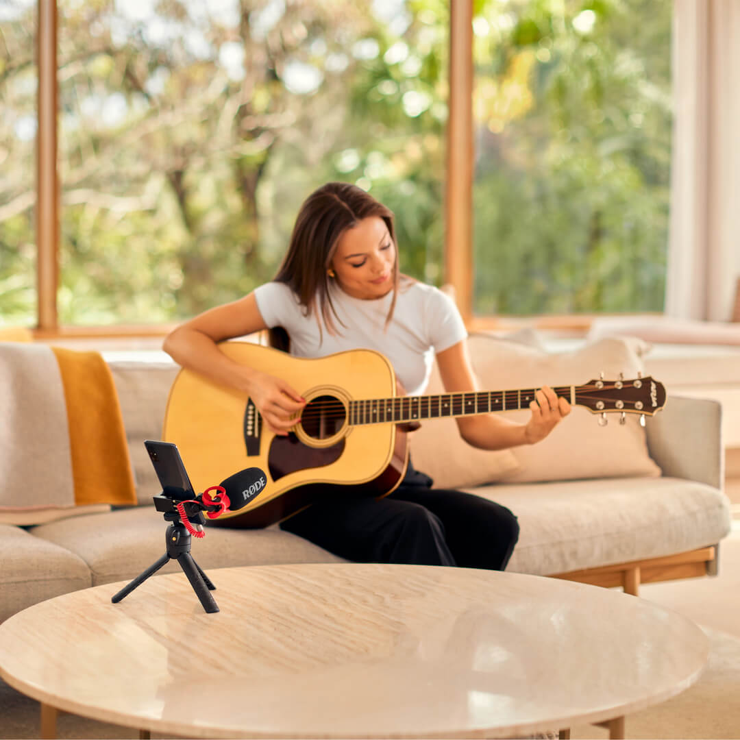 Girl playing guitar being recorded on mobile phone with VideoMicro II connected