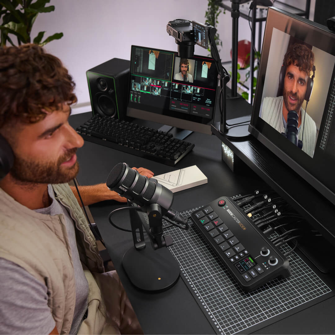 Person using PodMic USB and RØDECaster Video desk setup