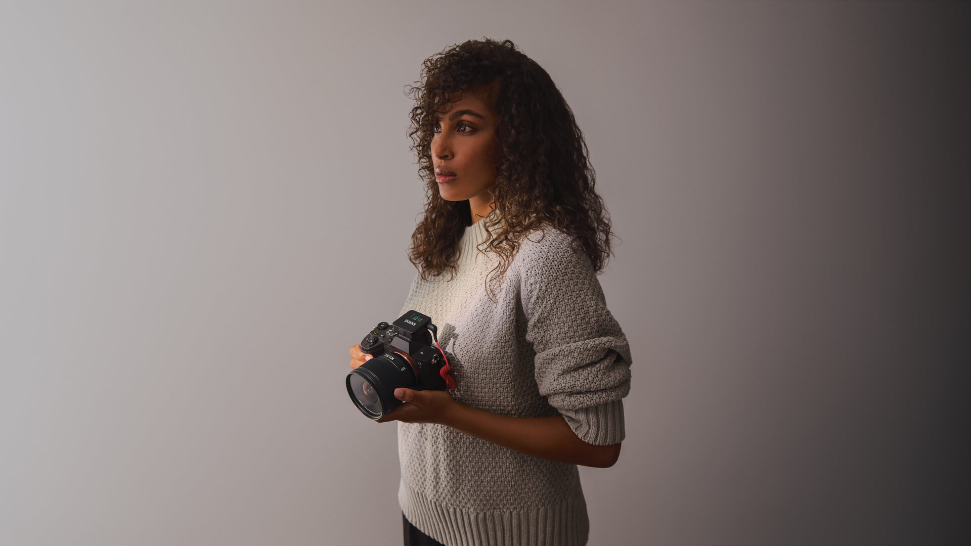 Girl in grey background holding camera with Wireless GO (Gen 3) connected