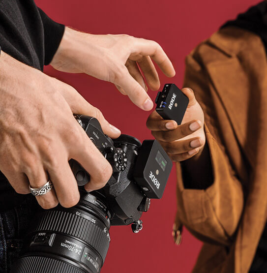 Camera with Wireless GO II receiver and hand reaching for transmitter